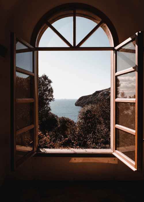 open window overlooking ocean and mountains, sign of a new beginning.